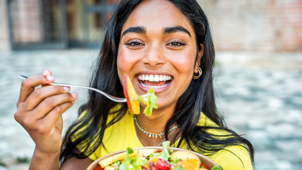 the woman smiles while eating the salad