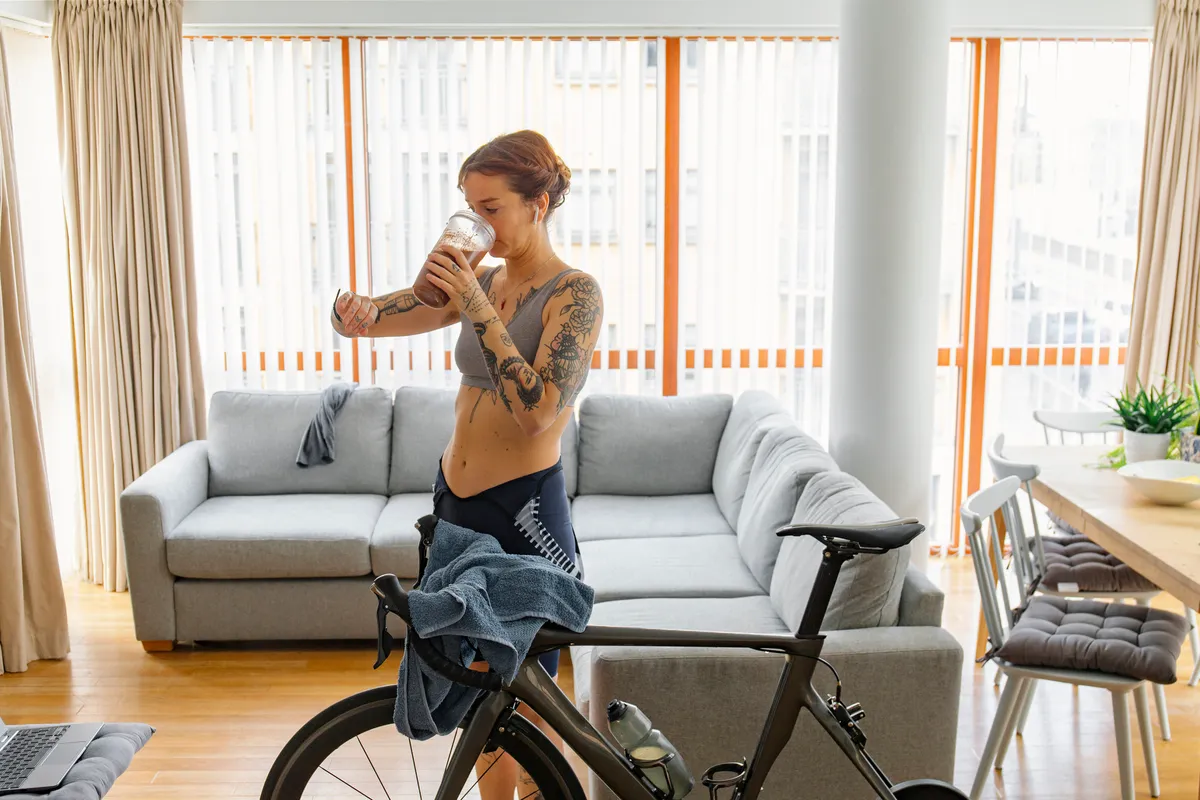 A woman checking her smartwatch after a hard workout on her indoor bike turbo trainer