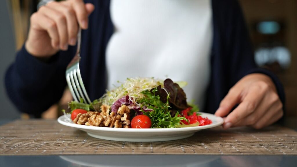 The woman is eating a salad